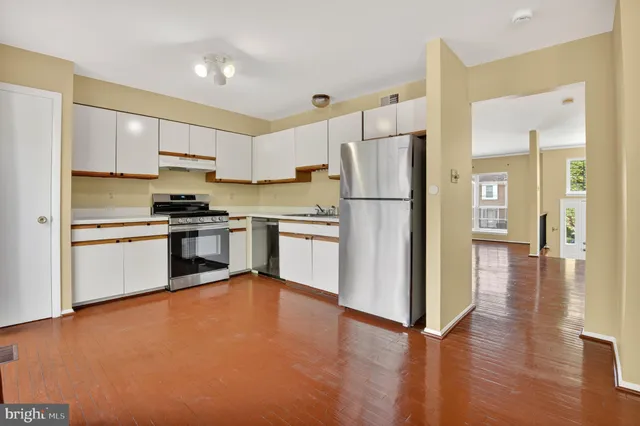 a kitchen with a refrigerator a stove top oven and cabinets
