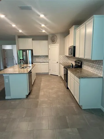 a large kitchen with stainless steel appliances granite countertop a stove top oven a sink dishwasher and cabinets