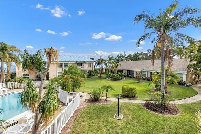 a view of a house with a yard and palm trees
