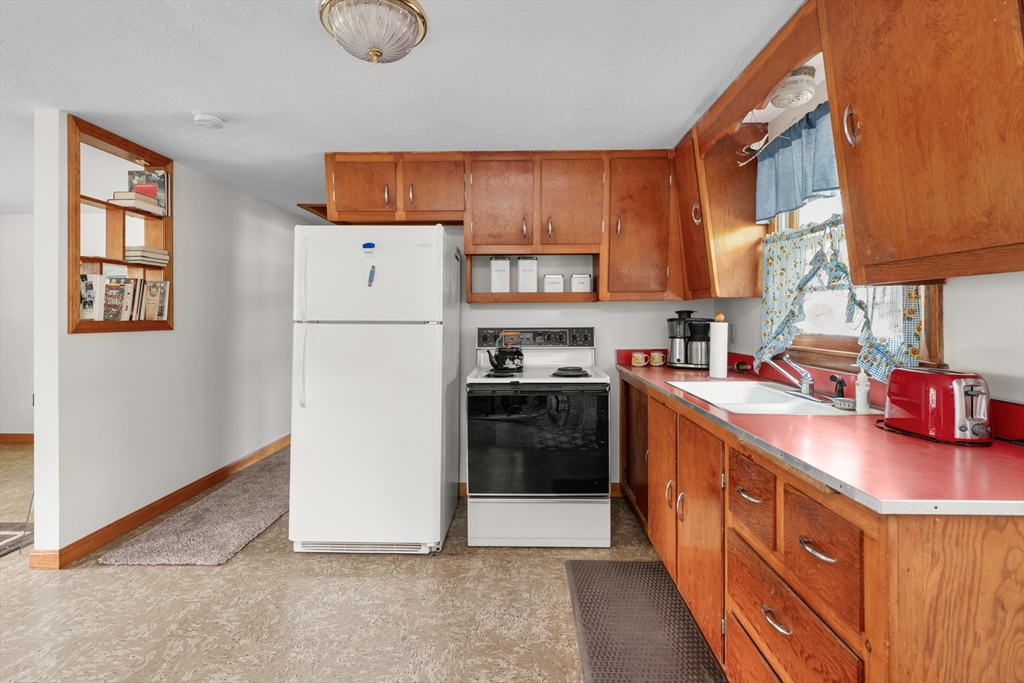 64 Uncle Percy's Road Mashpee, MA 02649 - Photo 10 of 33 a kitchen with stainless steel appliances granite countertop a refrigerator a sink dishwasher a stove and a dining table with wooden floor