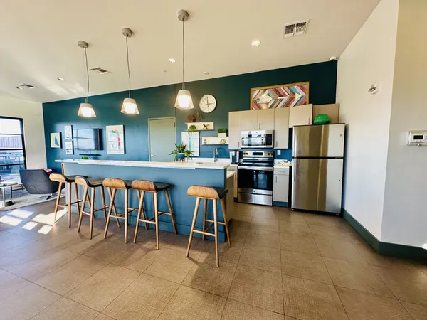 a kitchen with stainless steel appliances granite countertop a stove top oven a sink a dining table and chairs with wooden floor