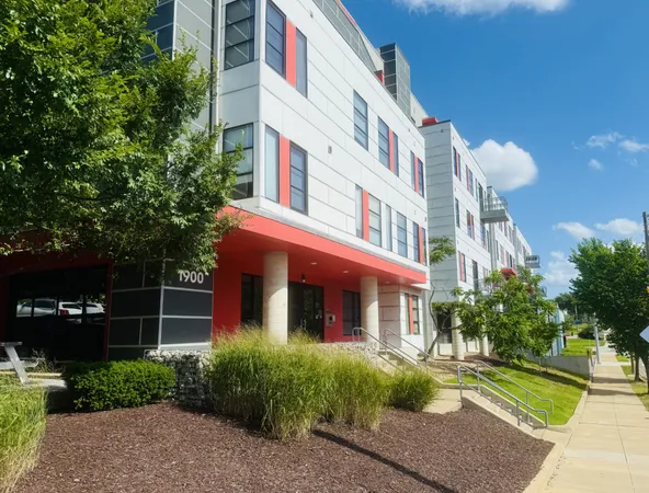 a front view of a multi story residential apartment building with yard and retail shops