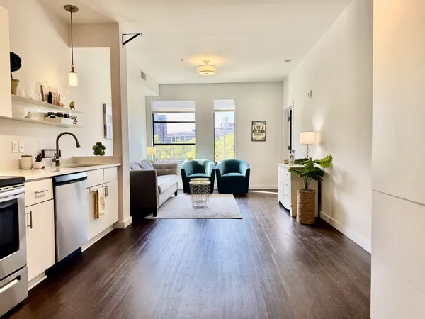 a large white kitchen with sink a refrigerator and wooden floor