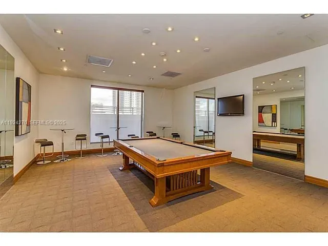 a room with furniture pool table flat screen tv and windows