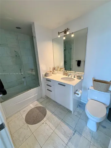 a bathroom with a granite countertop sink mirror vanity and toilet