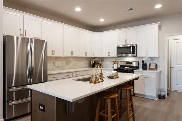 a kitchen with a sink a stove a refrigerator and white cabinets