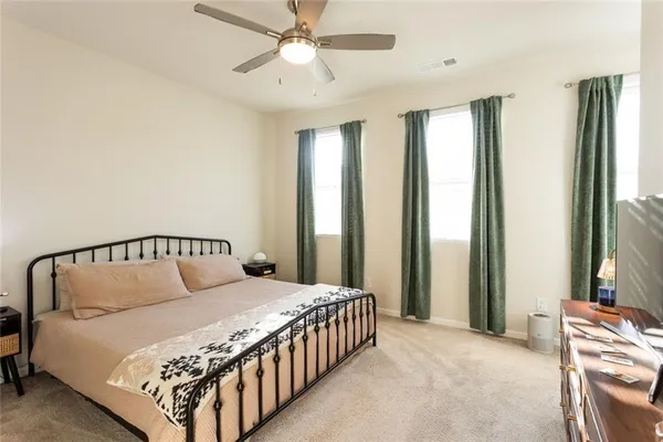 a large bed sitting in a bedroom next to a window and a chandelier