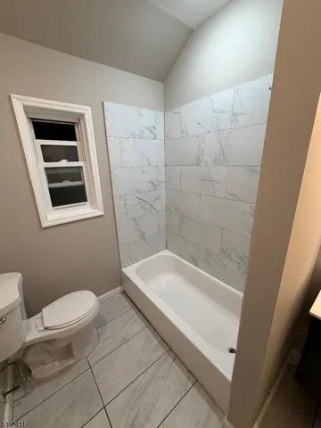 a bathroom with a granite countertop toilet a sink and bathtub