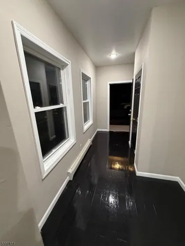 a view of an empty room with wooden floor and stairs