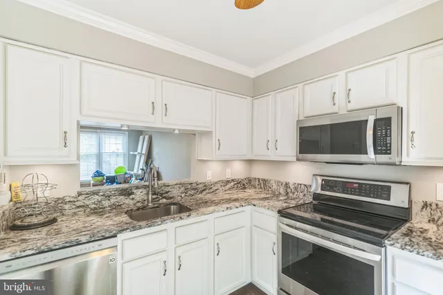 a kitchen with granite countertop a sink a stove and microwave
