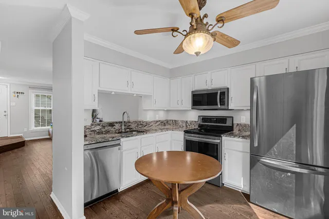 a kitchen with stainless steel appliances granite countertop a stove refrigerator a sink dishwasher with a dining table and chairs