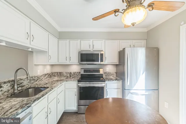 a kitchen with granite countertop a refrigerator stove and sink