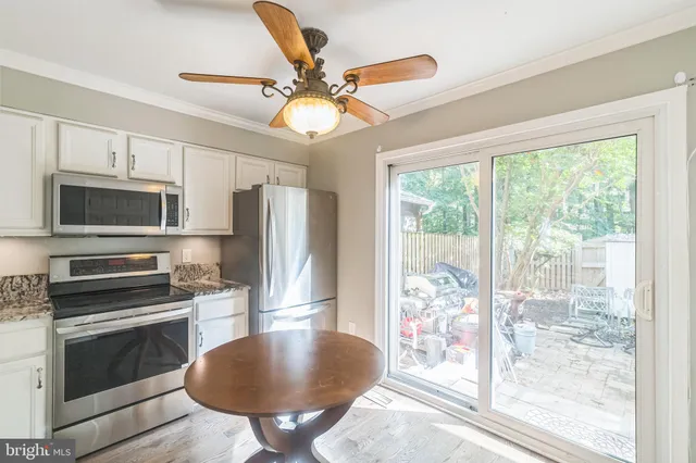 a kitchen with stainless steel appliances granite countertop a stove top oven a sink a refrigerator with a dining table and chairs