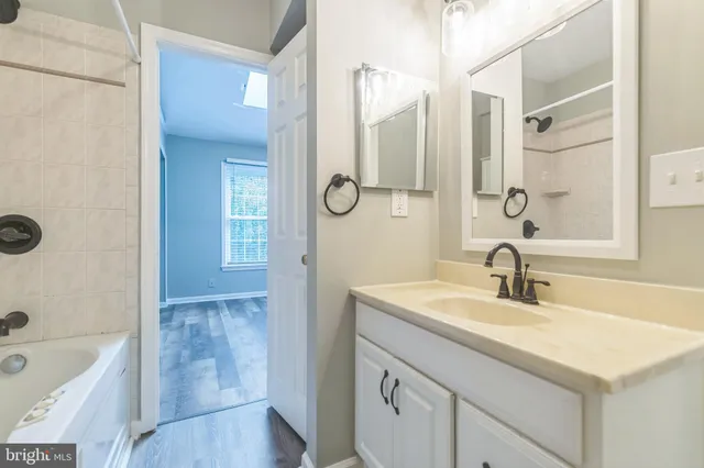 a bathroom with a sink double vanity granite tub shower and a mirror