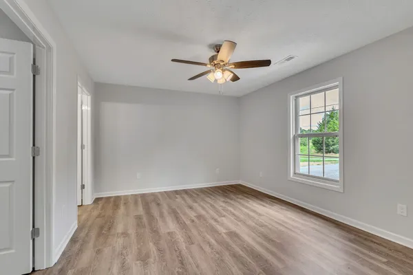 an empty room with wooden floor and windows