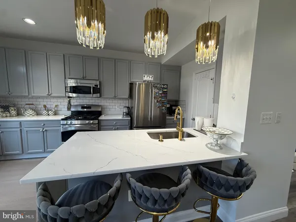 a kitchen with stainless steel appliances granite countertop a sink dishwasher a stove a refrigerator with a dining table and chairs