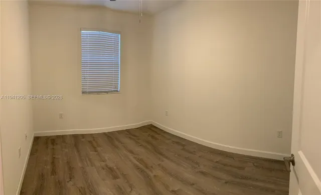 a view of a room with wooden floor and a window