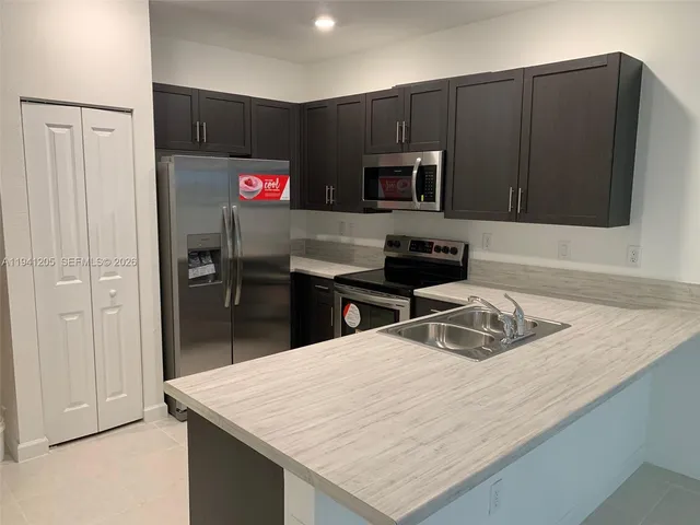 a kitchen with stainless steel appliances granite countertop a refrigerator sink and microwave