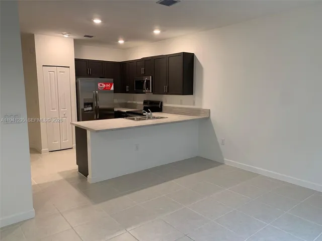 a view of kitchen with stainless steel appliances a sink and a refrigerator