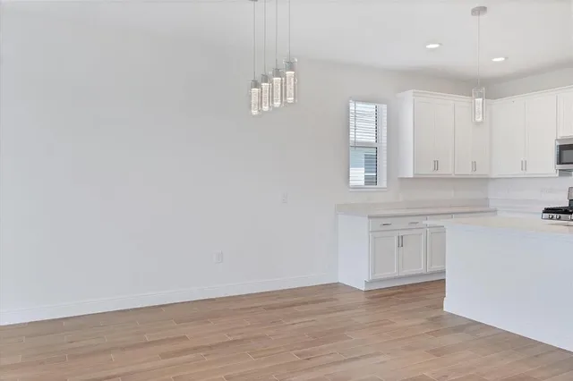 a view of an empty room with window and wooden floor