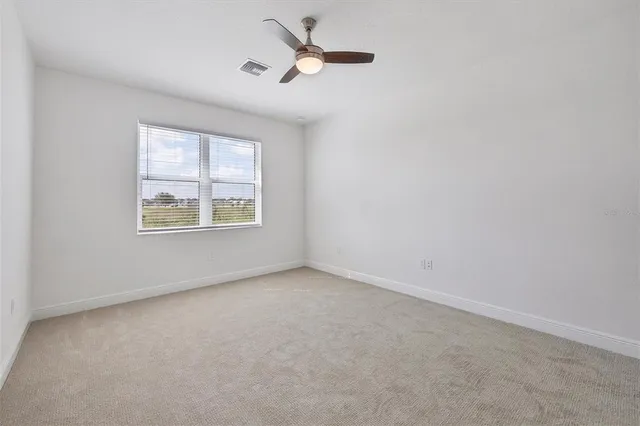 an empty room with windows and fan