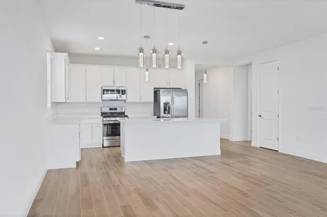 a kitchen with kitchen island a sink wooden floor and a refrigerator