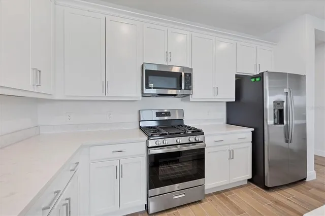 a kitchen with a refrigerator stove and white cabinets