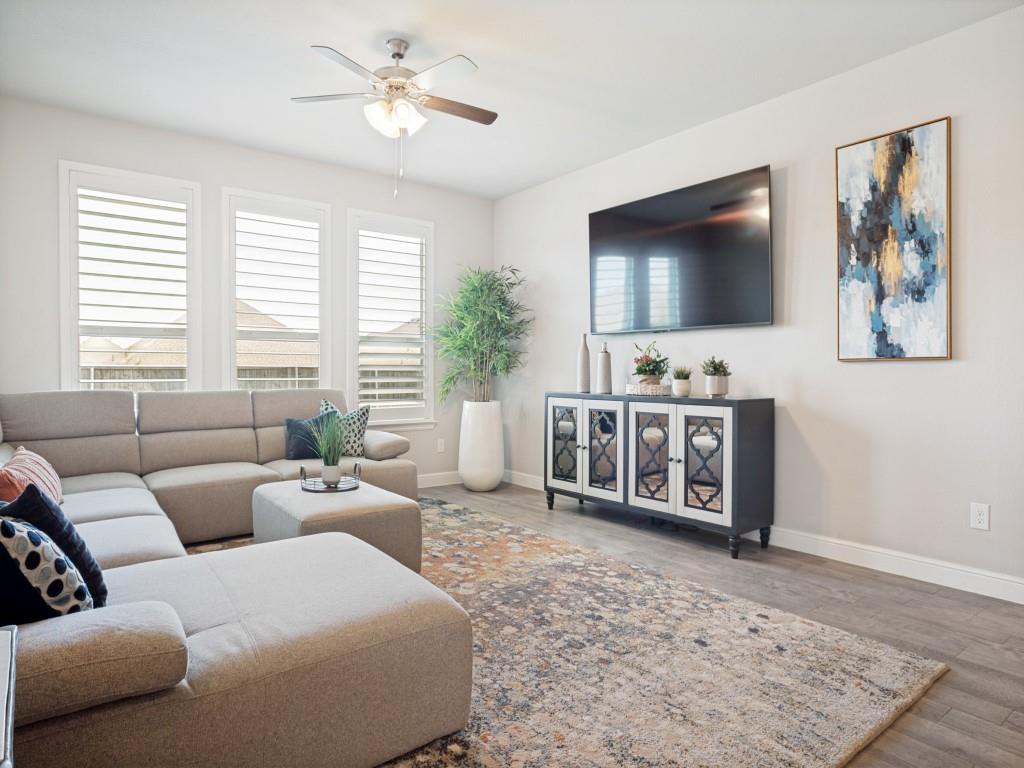 1612 Reed Drive Krum, TX 76249 - Photo 12 of 25 Living area featuring wood-finish flooring, a ceiling fan with integrated lighting, and multiple windows fitted with louvered shutters