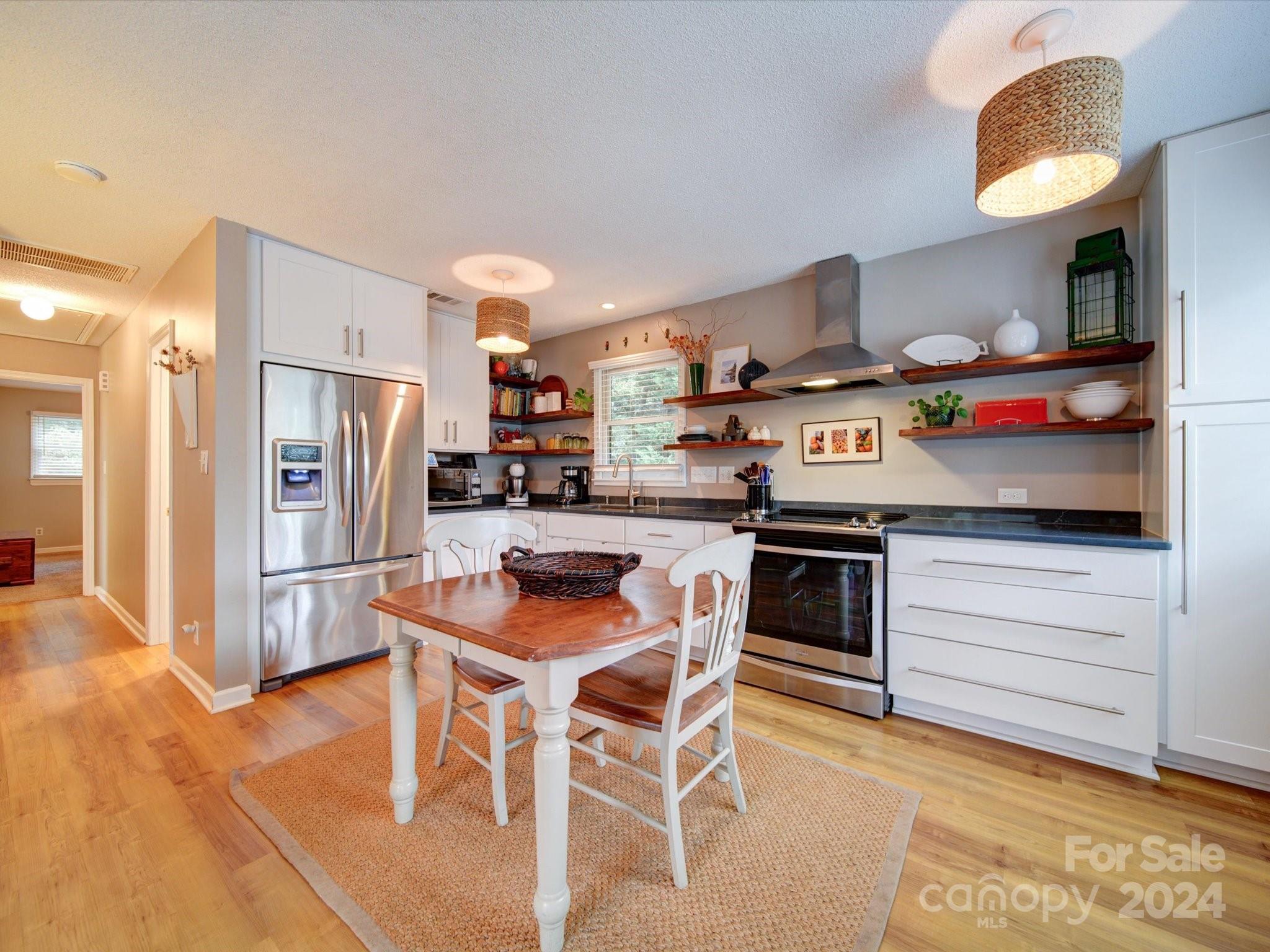 20126 Rainbow Circle Cornelius, NC 28031 - Photo 7 of 40 a kitchen with stainless steel appliances kitchen island granite countertop a table chairs stove and refrigerator
