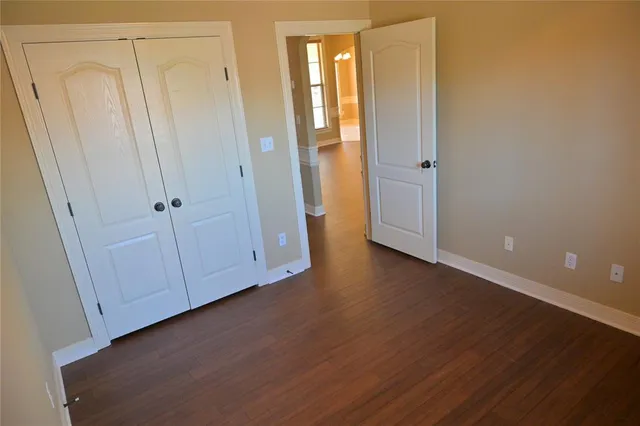 a view of an empty room with closet and wooden floor