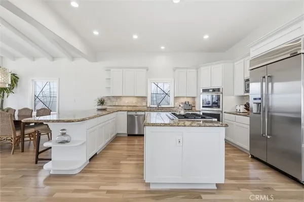 a kitchen with granite countertop a counter top space a sink cabinets and stainless steel appliances