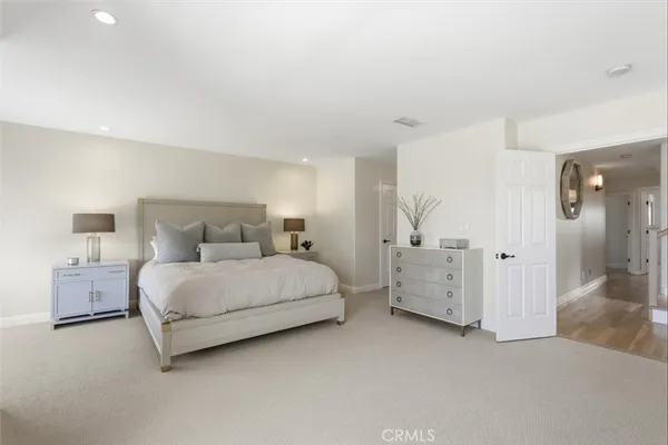 a spacious bedroom with a bed and painting on the wall
