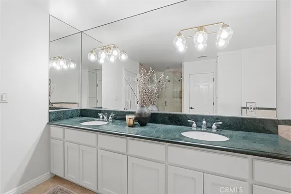 a bathroom with double vanity sinks a vanity a lamp and a mirror