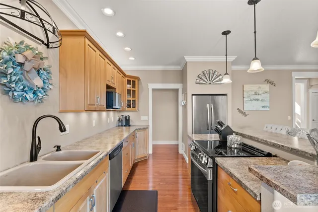 a kitchen with stainless steel appliances granite countertop a sink a stove and a wooden floor