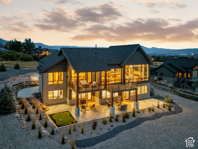 3929 Ridge Road Eden, UT 84310 - Photo 85 of 98 Stone and wood siding exterior with multiple balconies, expansive windows, a ground-level patio, and a putting green