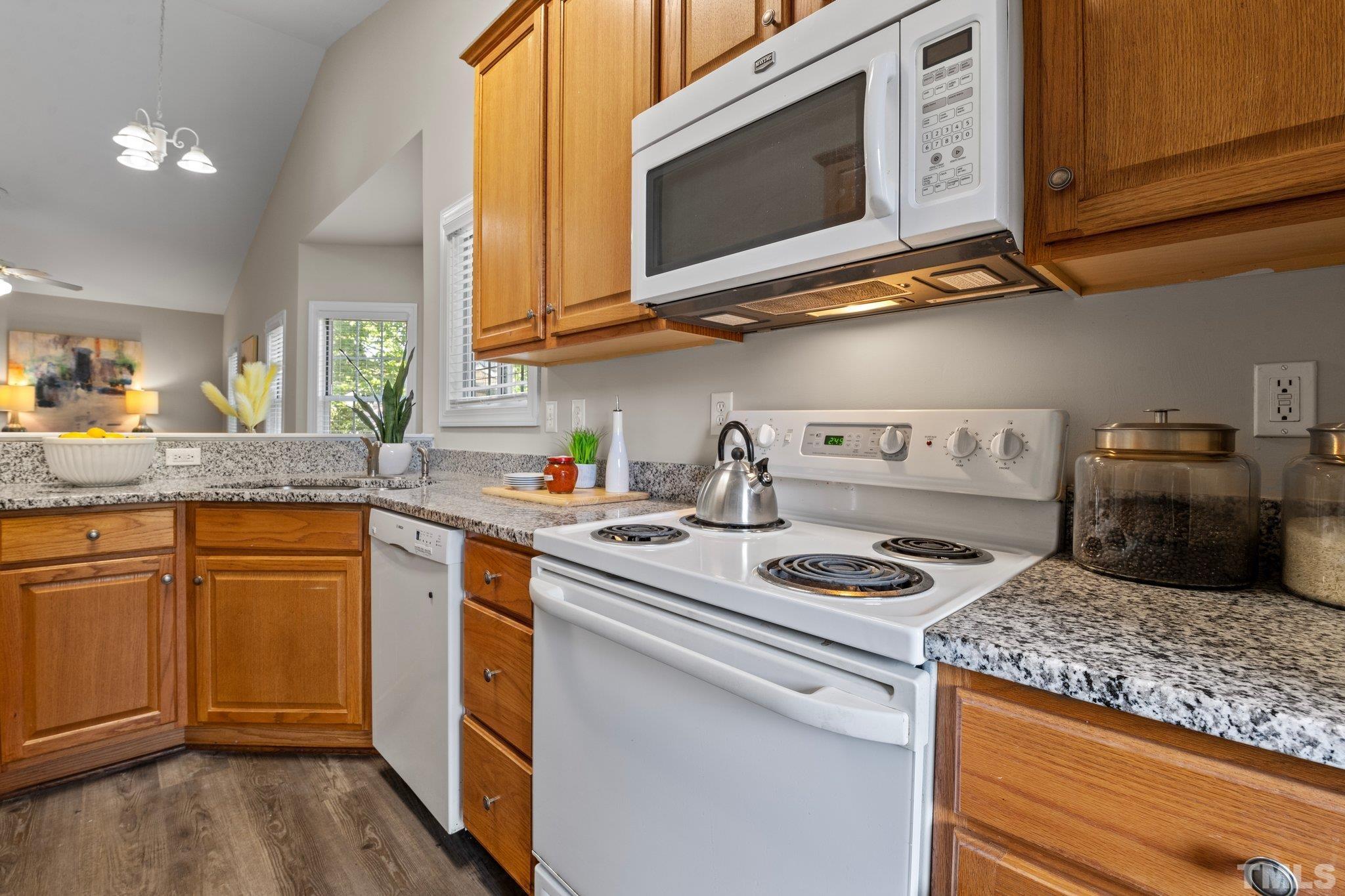 7024 Sandy Forks Road, Unit 302 Raleigh, NC 27615 - Photo 10 of 24 a kitchen with stainless steel appliances granite countertop a sink a stove a microwave cabinets and wooden floor