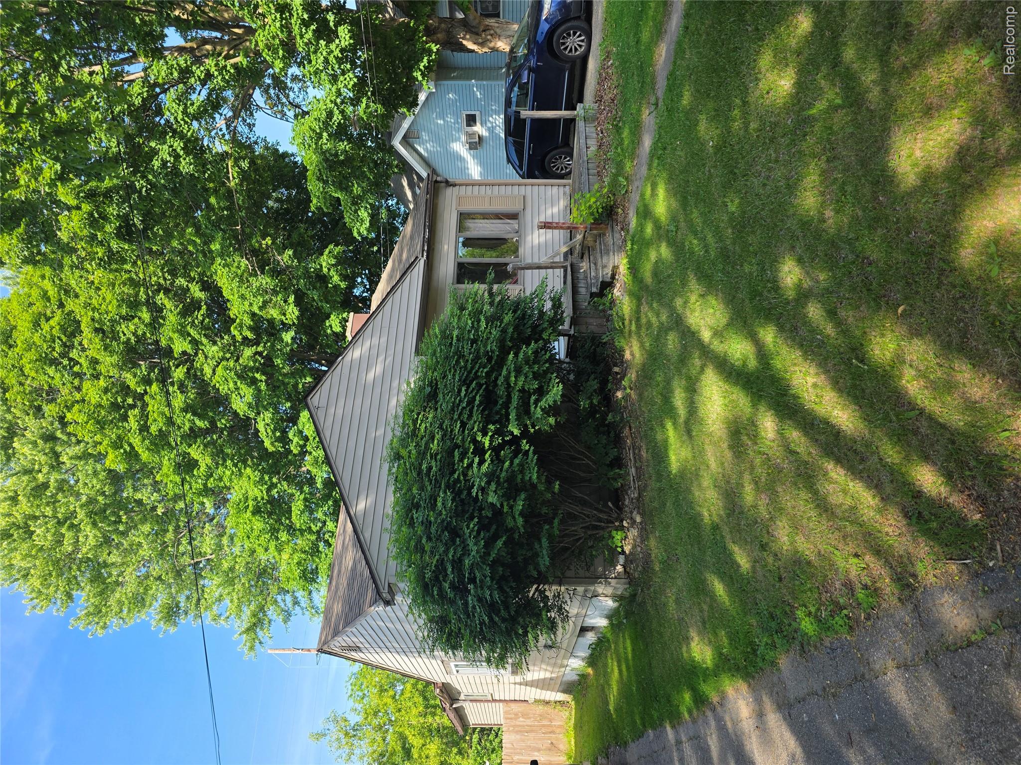 4217 Pengelly Road Flint, MI 48507 - Photo 2 of 26 Wood-sided residence featuring a front lawn, mature trees, and a concrete driveway