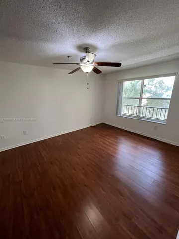an empty room with wooden floor chandelier fan and windows