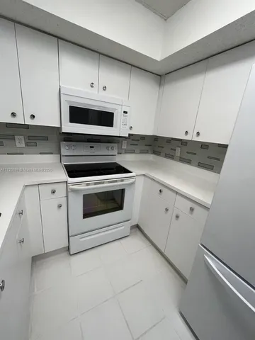 a kitchen with granite countertop white cabinets white stainless steel appliances and sink