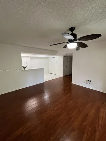 a view of a livingroom with wooden floor and a ceiling fan