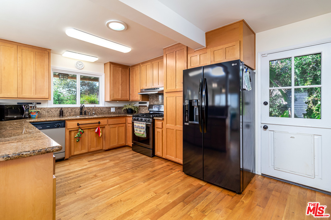 3938 Las Flores Canyon Road Malibu, CA 90265 - Photo 4 of 21 a kitchen with stainless steel appliances granite countertop a refrigerator a sink a stove and white cabinets with wooden floor