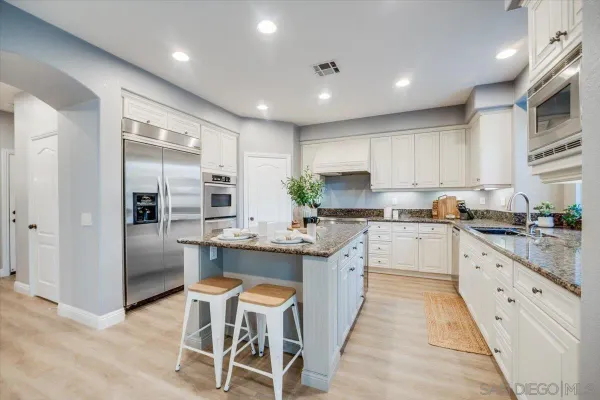 a kitchen with kitchen island granite countertop lots of counter top space and stainless steel appliances