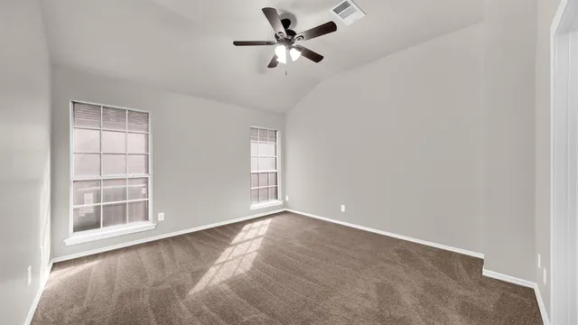 an empty room with windows and fan