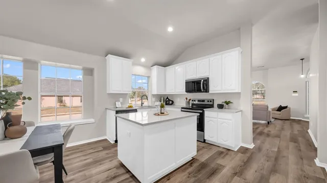 a kitchen with stainless steel appliances kitchen island granite countertop a stove top oven a sink a dining table and chairs