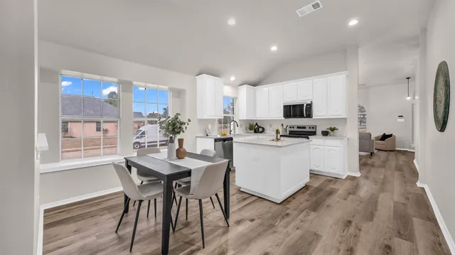 a kitchen with a table chairs refrigerator and cabinets