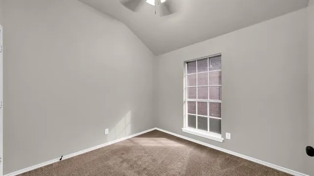 an empty room with chandelier fan and windows