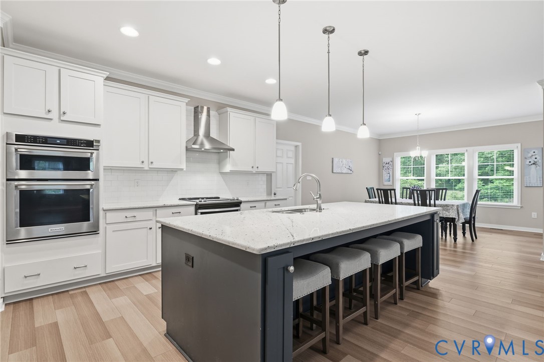 7598 Rural Point Road Mechanicsville, VA 23116 - Photo 11 of 41 a kitchen with stainless steel appliances granite countertop a stove a refrigerator a kitchen island a sink a dining table and chairs with wooden floor