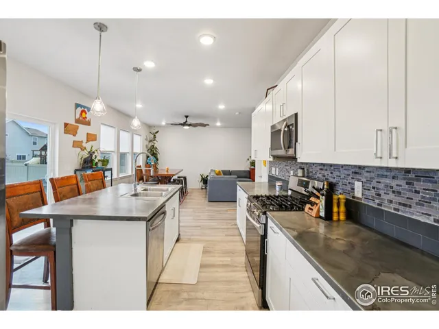 a kitchen with stainless steel appliances granite countertop a sink a stove and a wooden cabinets