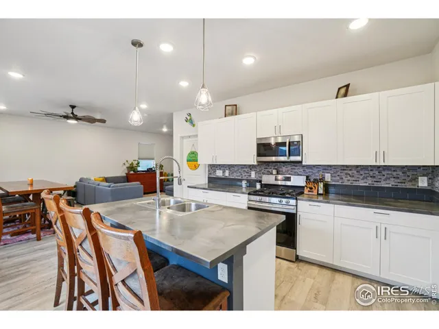a kitchen with stainless steel appliances kitchen island granite countertop a stove a sink a dining table and chairs