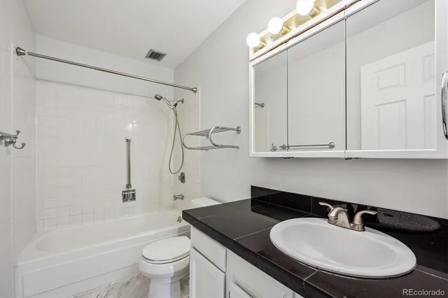 a bathroom with a granite countertop sink a toilet a mirror and shower